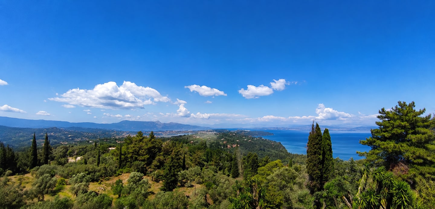 A wide view over the green landscape and blue sea of Corfu